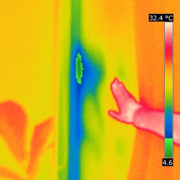 Operator kamery termowizyjnej ręką wskazuje brak pianki montażowej skraplanie się wody na styku okno-mur